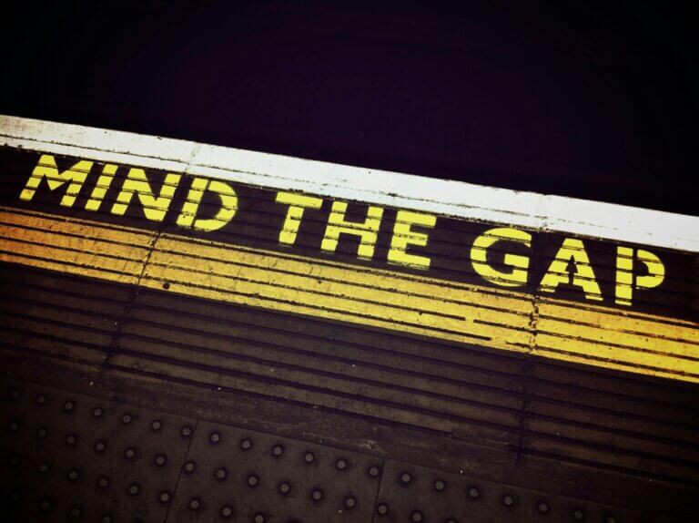 Bold 'Mind the Gap' text on a subway platform, emphasizing passenger safety.