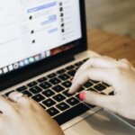 Close-up of hands typing on a laptop keyboard with a messaging app open on the screen.